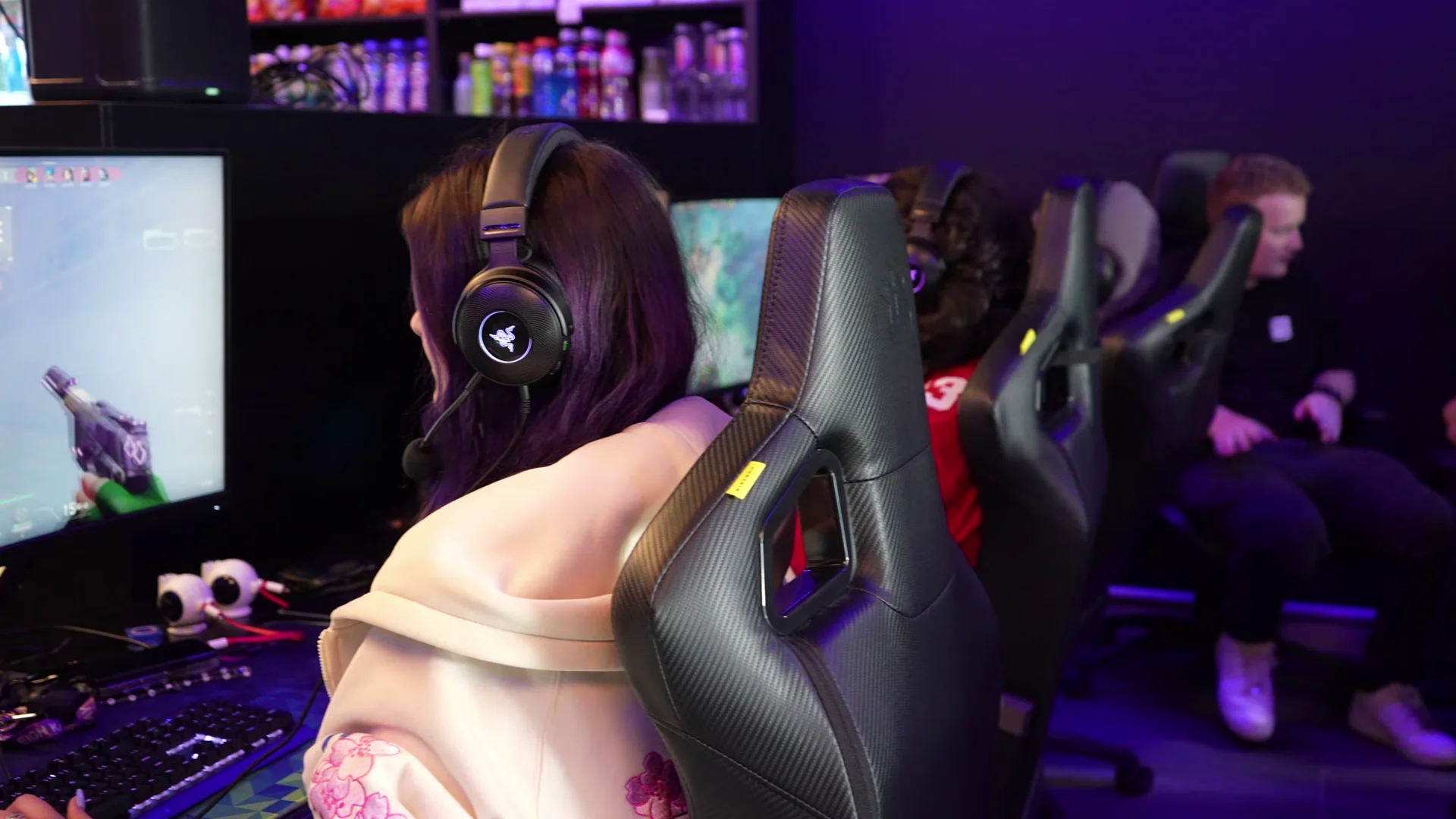 A player in a headset at a Gala Clayton gaming PC, with rows of black gaming chairs behind